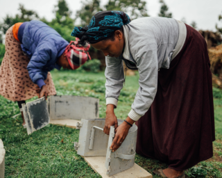 ﻿En gruppe kvinner får opplæring i å bygge rentbrennende ovner.