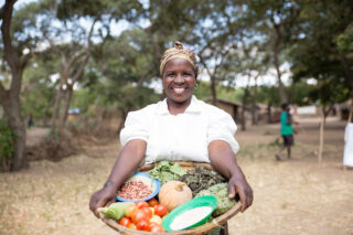 Grace Madzi (47), følgebonde, viser frem vekster hun dyrker på gården sin i Malawi.