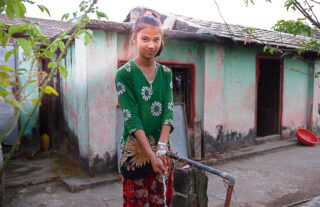 Girl in Nepal in front of water pump